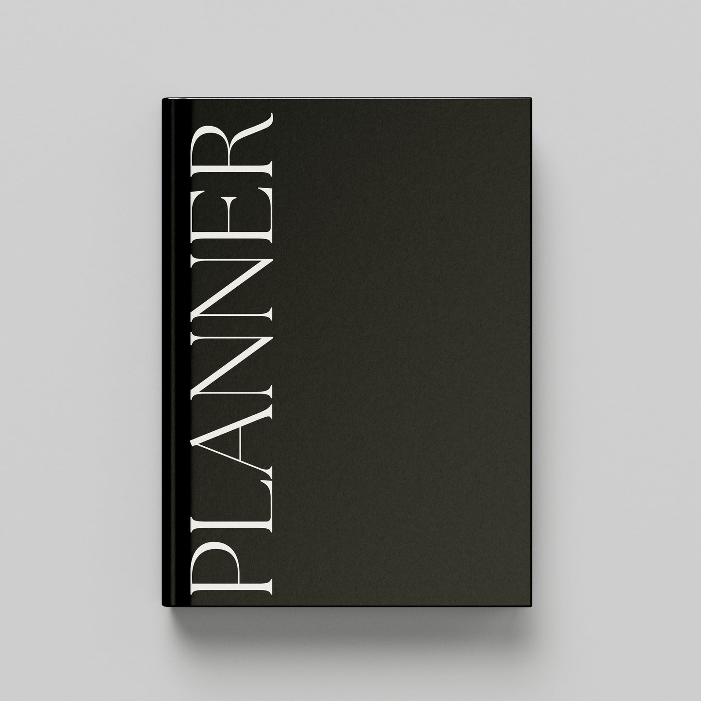 A black hardcover planner with the word 'PLANNER' printed vertically in white serif lettering on the front cover, shown against a light grey background.