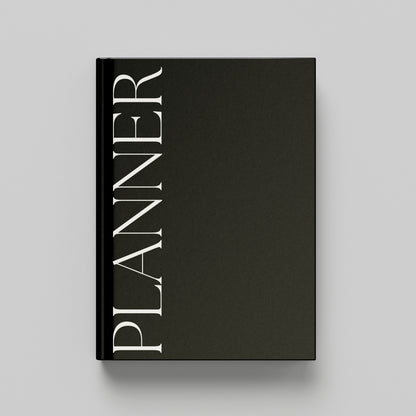 A black hardcover planner with the word 'PLANNER' printed vertically in white serif lettering on the front cover, shown against a light grey background.
