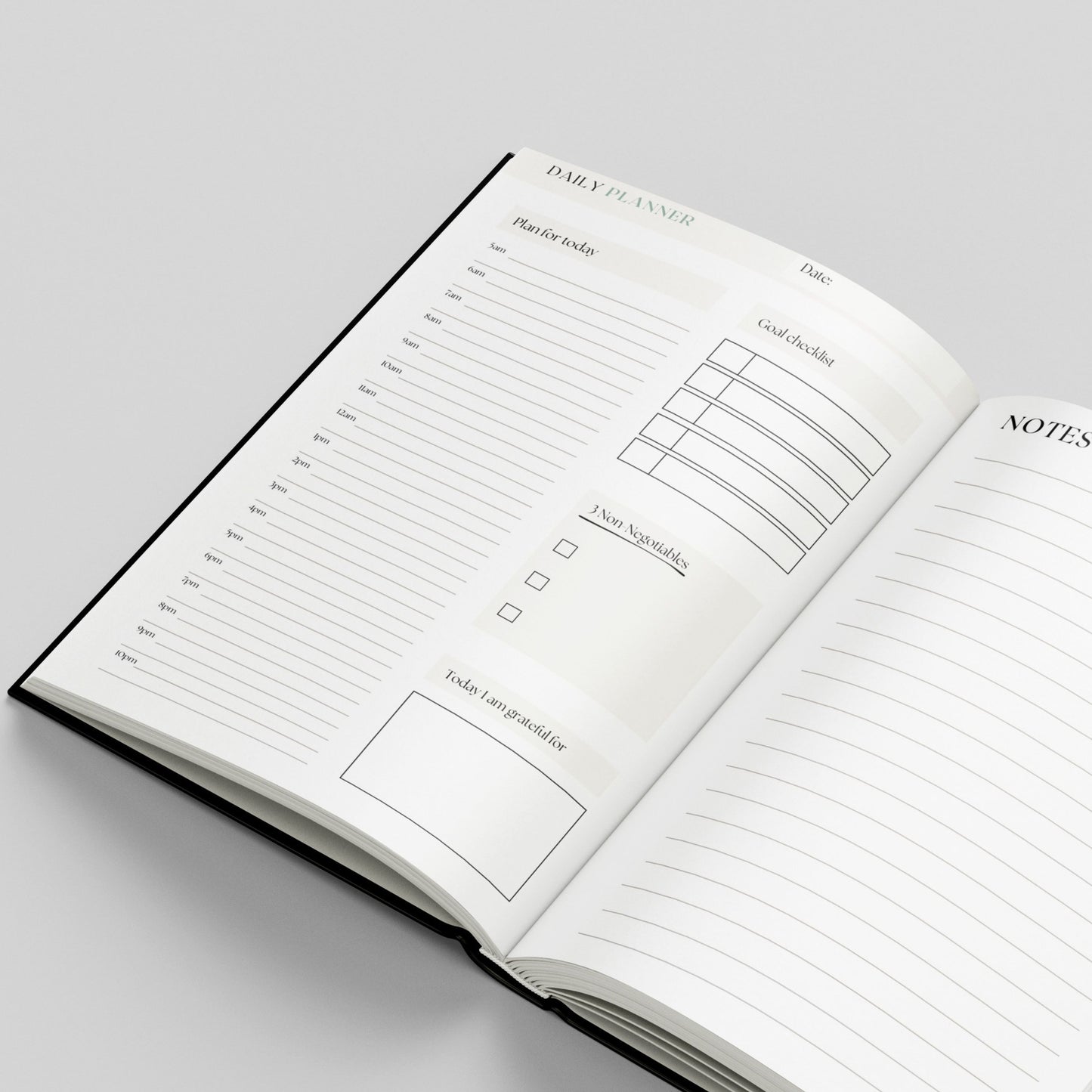 An open hardcover daily planner notebook on a light grey background, showing lined pages with sections for a daily planner, goal checklist, notes, and task boxes.