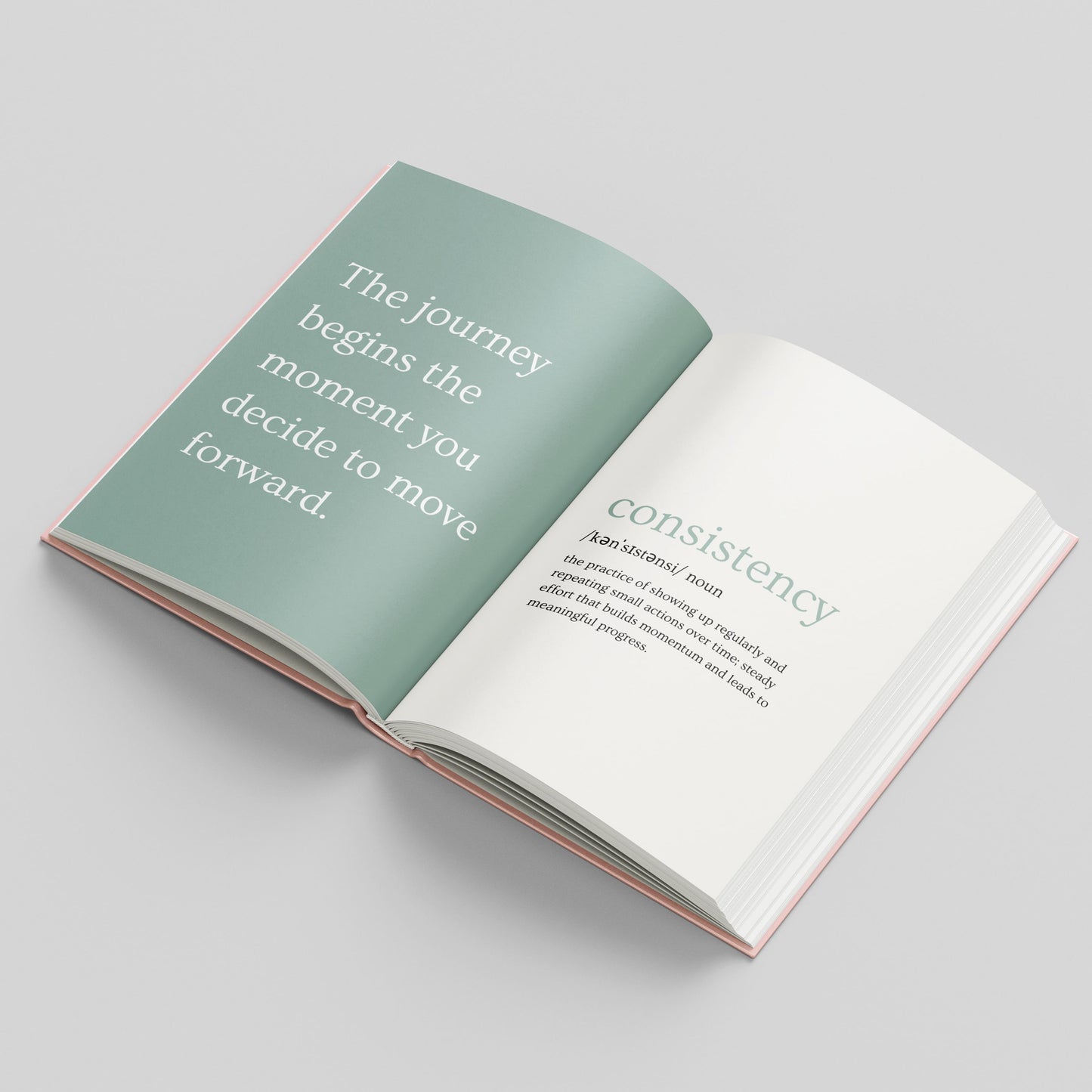 An open book laid flat on a light grey background, showing two interior pages with white and pale green typography. The left page has a large quote in white text on a muted sage-green background, and the right page has a definition under the word 'consistency.