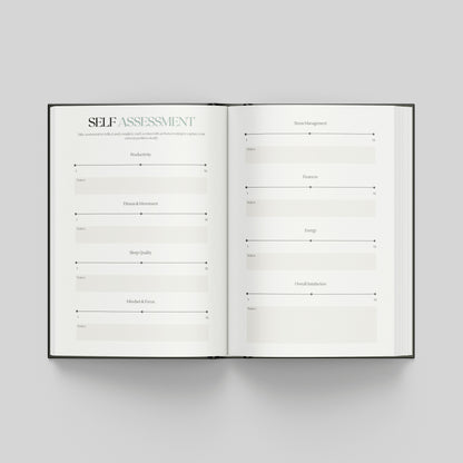 An open hardcover book showing two white pages with a self-assessment template layout, photographed from above on a light grey background.
